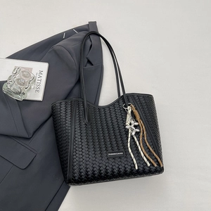 Detail of black woven tote bag with Fashion & Bags logo plate and decorative charm