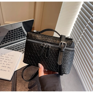 Detalle de la textura de cuero trenzado negro de un bolso bandolera estilo vanity