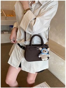 Detail of vintage brown leather tote bag featuring a cute bear pendant and top handle