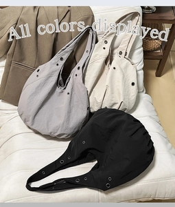 Détail de trois cabas en nylon plissé gris, crème et noir avec des œillets métalliques