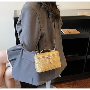 Detalle de bolso amarillo brillante con textura trenzada, asa curva y doble cremallera