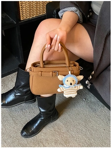 Brown lychee grain tote bag detail with decorative buckle and cute knit bear charm
