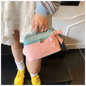 Close-up of pink and blue contrast leather handbag with lychee texture and bow detail