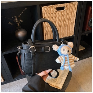 Close-up of black lychee-textured tote bag featuring a cute teddy bear plush charm