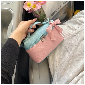 Detail of color-block lychee leather handbag with bow and Fashion & Bags text