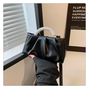 Detail showing black ruched leather bag texture with white pearl beaded handle strap