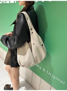 Détail d'un grand sac bandoulière beige plissé avec œillets métalliques porté par un mannequin