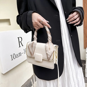 Détail du sac crème avec texture crocodile et poignée ornée d'un foulard en soie