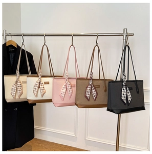 Row of quilted tote bags in five colors with decorative silk scarves hanging on display