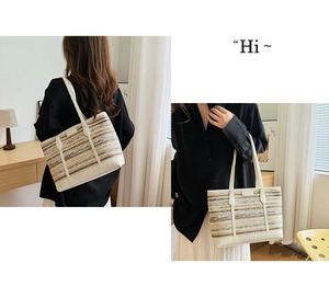 Close-up of the striped straw tote bag featuring contrast stitching and white leather handles
