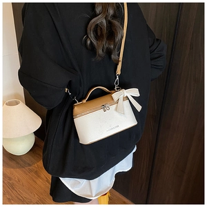 Detail of lychee textured contrast handbag with white bow and brown leather strap