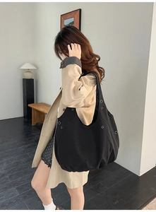 Détail du grand sac bandoulière en toile noire avec œillets argentés et plis stylés