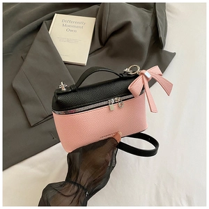 Close-up of litchi grain texture and bow decoration on pink and black crossbody bag