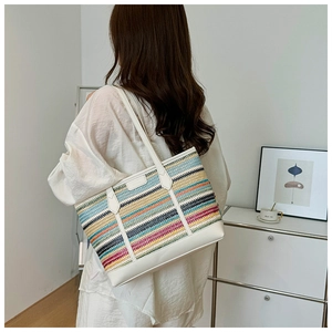 Detail of colorful striped woven tote bag with white leather handles and refined texture