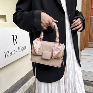 Détail du sac beige avec motif crocodile et poignée décorée d'un foulard en soie