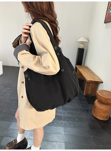 Détail d'un grand sac hobo noir avec des œillets métalliques argentés et décoratifs