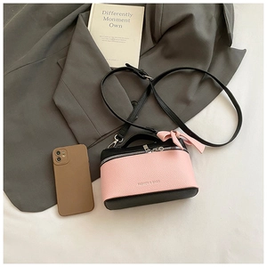 Flat lay of pink and black color-block lychee grain bag with a bow detail and metal zipper