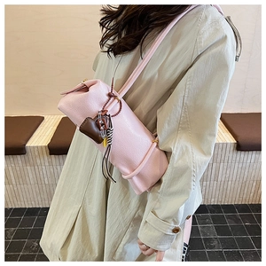 Detail of pink lychee leather shoulder bag with heart charm and woven tassel details