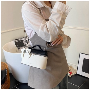 Detail of lychee pattern leather handbag featuring a large white bow and silver hardware