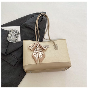 Detail view of woven tote bag with khaki leather trim and houndstooth silk scarf accent