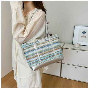 Detail of multi-color woven tote bag with wavy patterns and silver brand plate