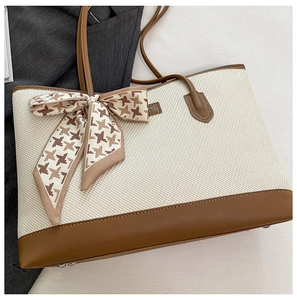Detail of off-white woven tote with brown leather trim and houndstooth ribbon bow