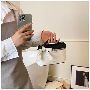 Detailed view of the contrast-color box bag with lychee texture and large side bow