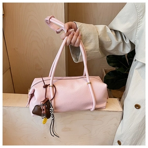 Close-up of pink barrel bag showing fine leather texture and golden zipper detail
