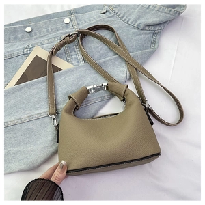 Detail view of khaki pebbled leather shoulder bag with silver buckle and adjustable strap