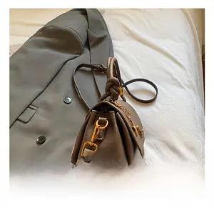 Detailed macro of brown lychee grain leather handbag with gold twist lock and knot handle