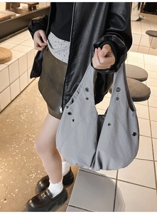 Détail du sac cabas gris plissé avec œillets métalliques et large bandoulière mode