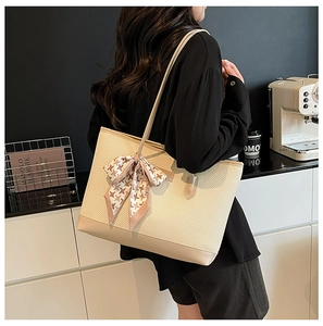 Close-up of beige quilted tote bag with elegant pink houndstooth bow scarf detail