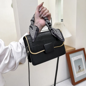 Détail d'un sac à main noir en cuir PU avec motif crocodile, bord doré et poignée en soie