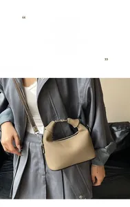 Detail of tan lychee grain leather bag featuring silver metal ring handle and strap