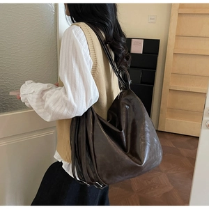Detail of dark brown leather tote bag showing slouchy aesthetic and side straps