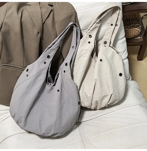 Détail de cabas plissés gris et beige avec œillets métalliques sur un canapé blanc