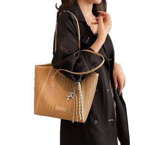 Brown woven tote bag with shoulder strap and balloon dog charm for daily commute
