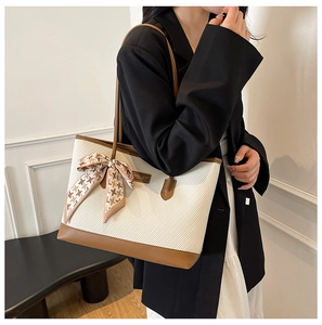 Detail of off-white woven tote bag with brown leather trim and houndstooth silk ribbon