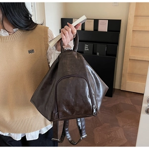 Detailed side view of a vintage dark brown triangle backpack with adjustable straps