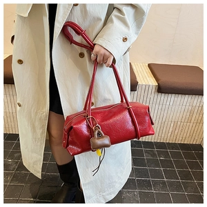 Detail of red glossy bowling bag with a brown lock charm and long shoulder straps