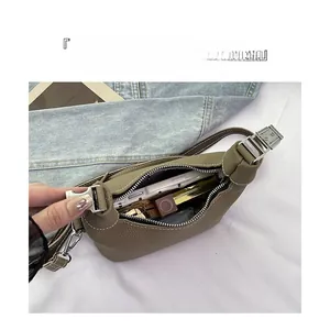 Internal storage detail of khaki crescent bag showing phone and lipstick capacity