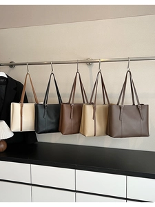 Dettaglio di borse tote in cinque colori diversi appese su un espositore da boutique