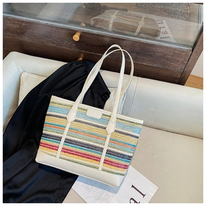Detail of multi-color woven tote bag with beige leather trim on a luxury leather sofa