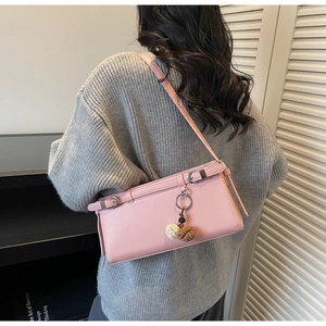 Détail d'un sac à bandoulière en cuir rose avec boucles et breloque pompon bicolore