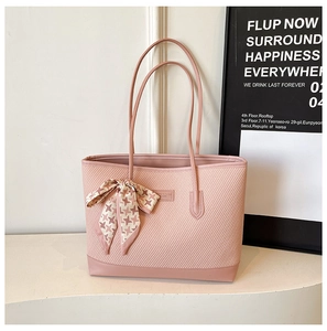 Pink tote bag with woven texture and decorative silk scarf bow on a minimalist display