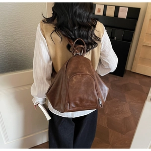 Detailed back view of a brown vintage leather backpack with triangular cut and silver zipper