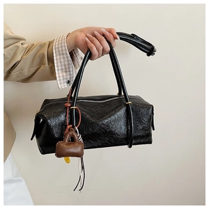 Detail of black rectangular glossy crinkle bag with brown mini charm and beads