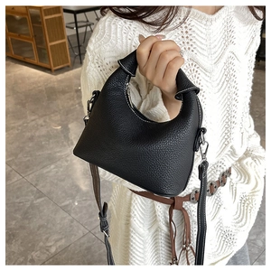 Detail of black lychee grain leather handbag with silver buckle and sleek single handle