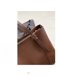 Dettaglio borsa in pelle marrone scuro con cuciture bianche e fibbia in metallo oro