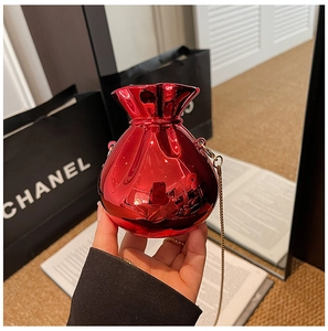Close-up of red metallic drawstring bucket bag with gold chain strap in hand
